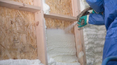 Spray foam technician spraying insulation on wood frame